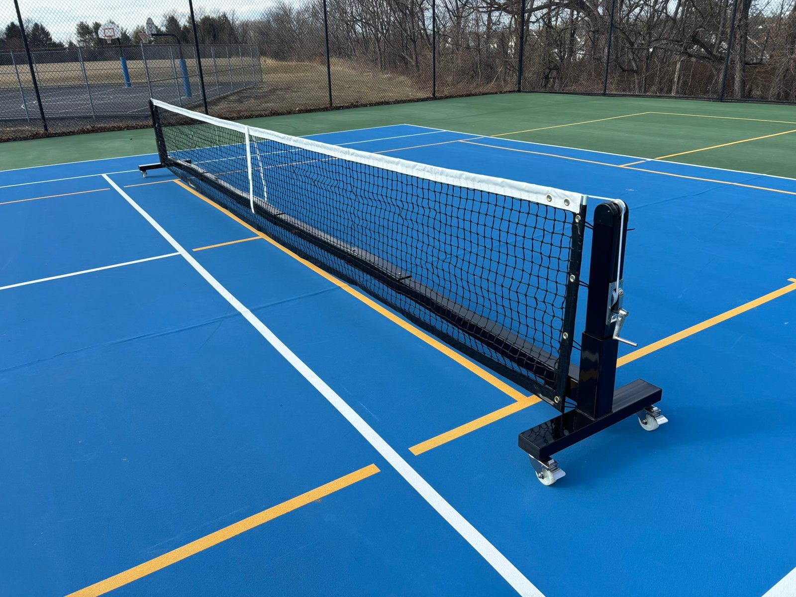 Pro Heavy Duty Portable Pickleball Net | Optional Wheels 6 Portable pickleball net on wheels set up on a blue hard court showing full 22-foot span.